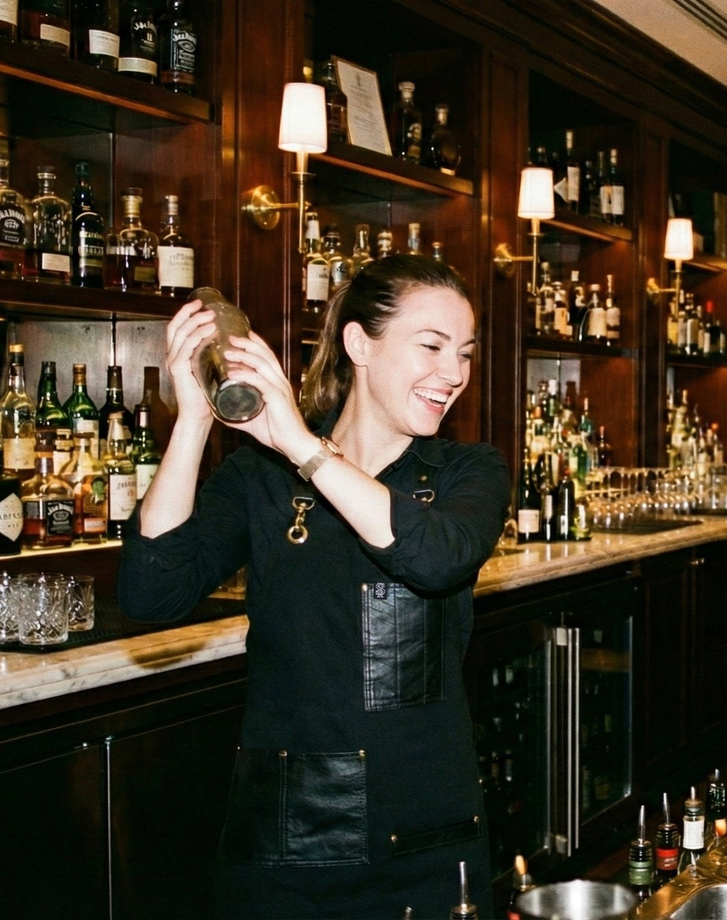 Bartenders at a bar preparing drinks with bottles and glasses in the background